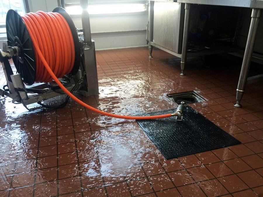 Hydro jetting hose feeding a kitchen floor cleanout — grease trap cleaning in Fullerton, CA