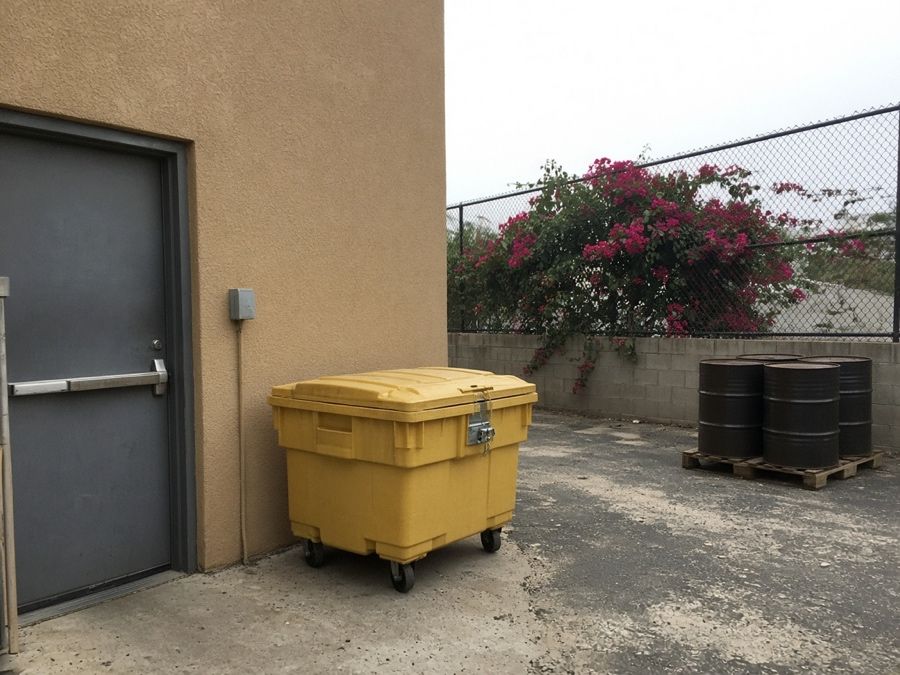 Sealed used cooking oil collection bin beside a rear kitchen door — grease trap cleaning in Fullerton, CA